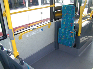 Tip-up seat and wheelchair area featuring powered wheelchair arm
